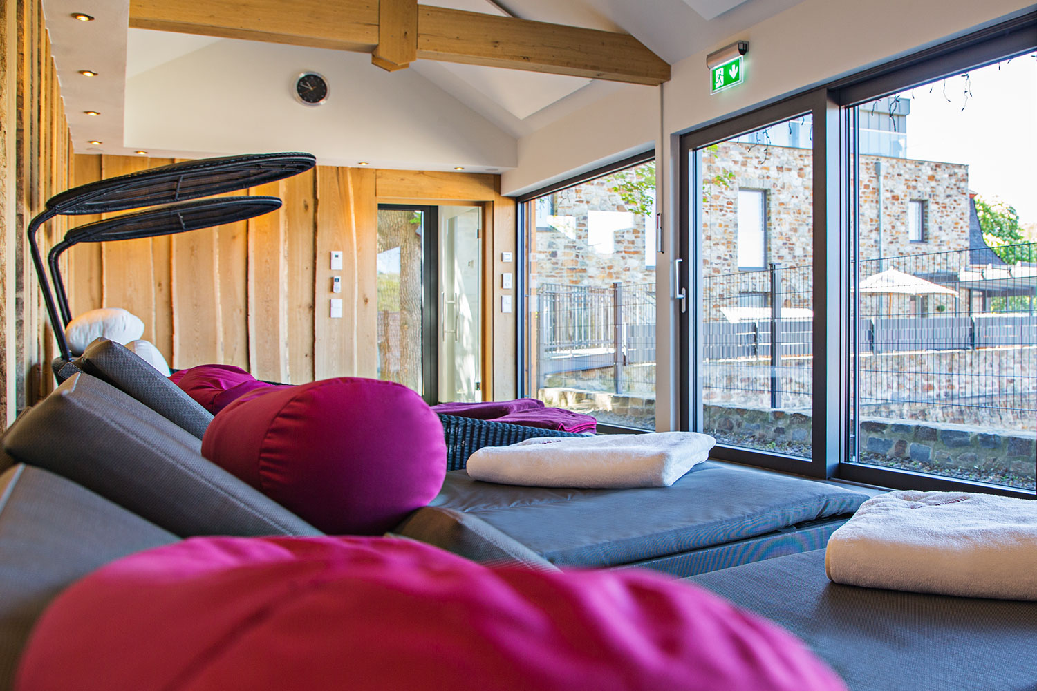 Ruheraum Sauna mit Entspannungsliegen und Blick auf Dachterrasse Wellnessbereich